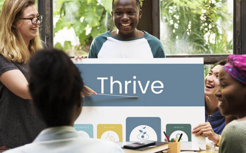 a person holding a sign that says thrive